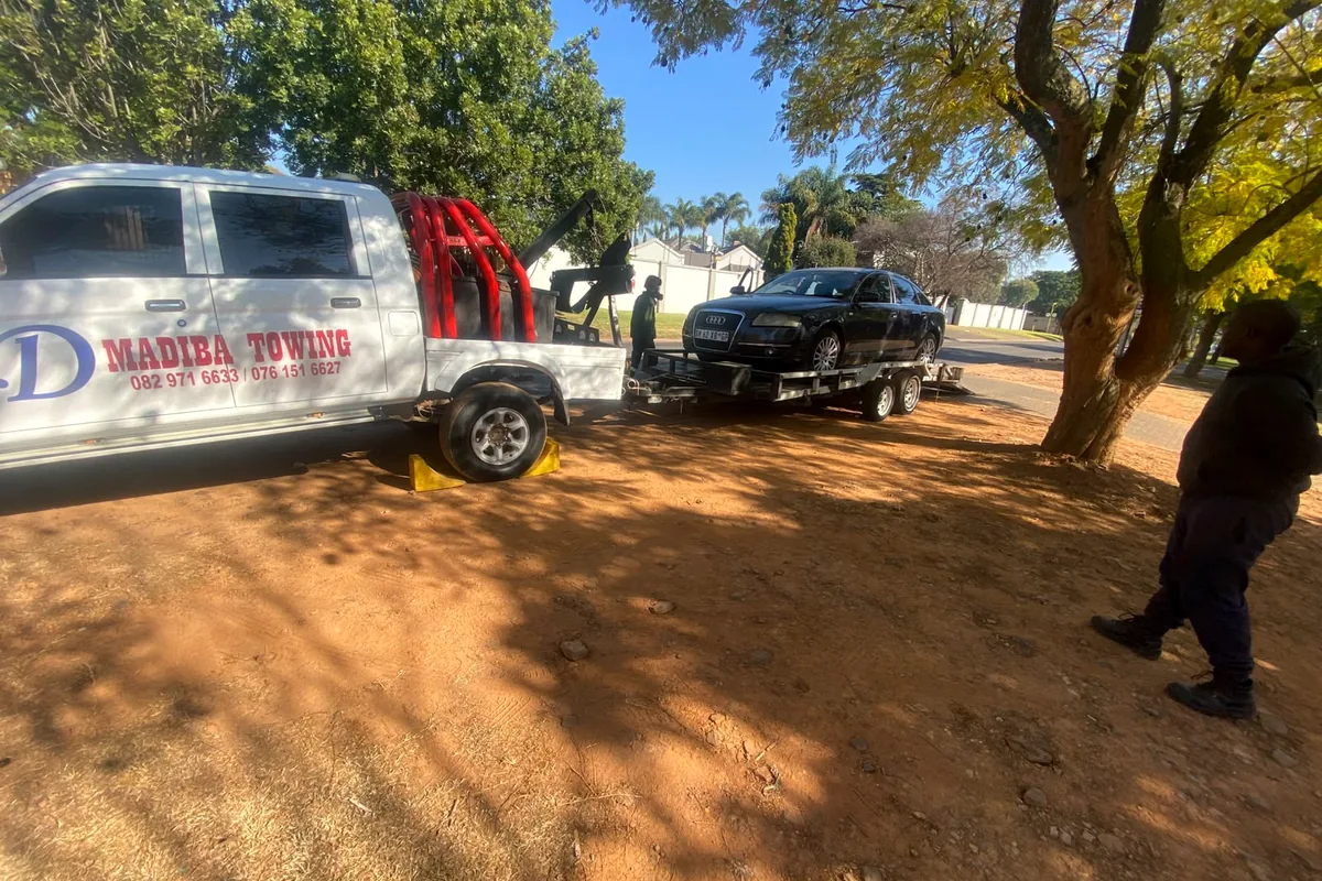 Tow vehicle and trailer transporting a black sedan