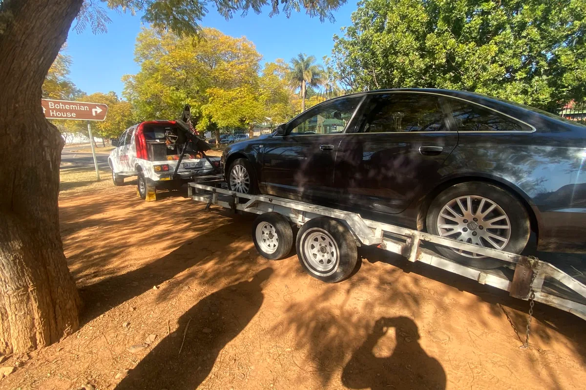 Side view of a black sedan secured on a double-axle trailer